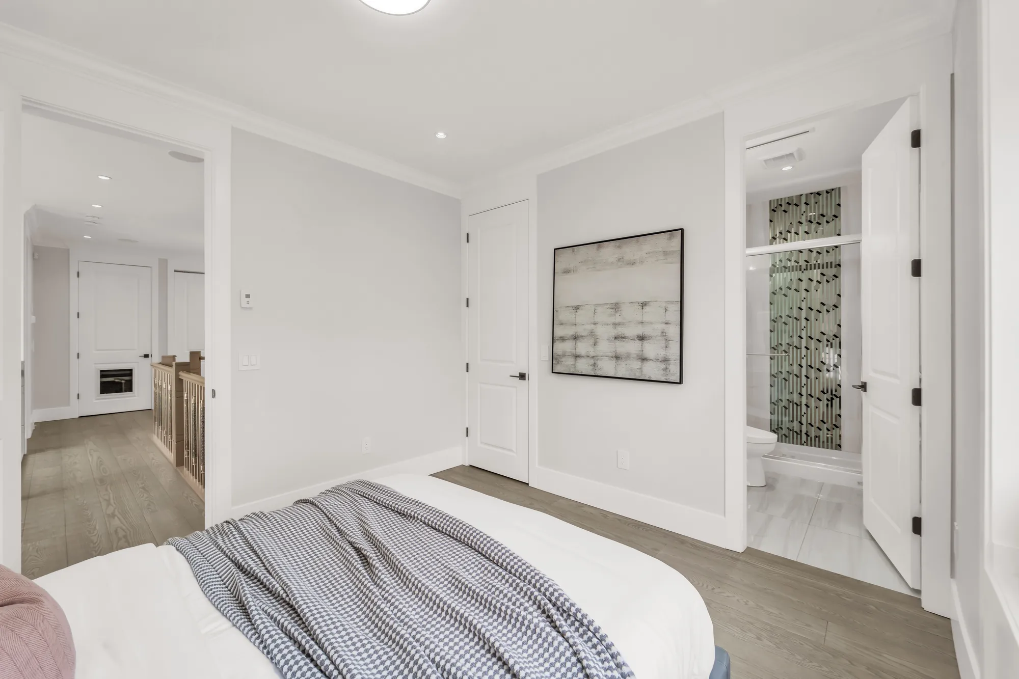 The same bedroom toward its doors: a bathroom with a mosaic-tiled shower through the open door at the right, the hall at the left