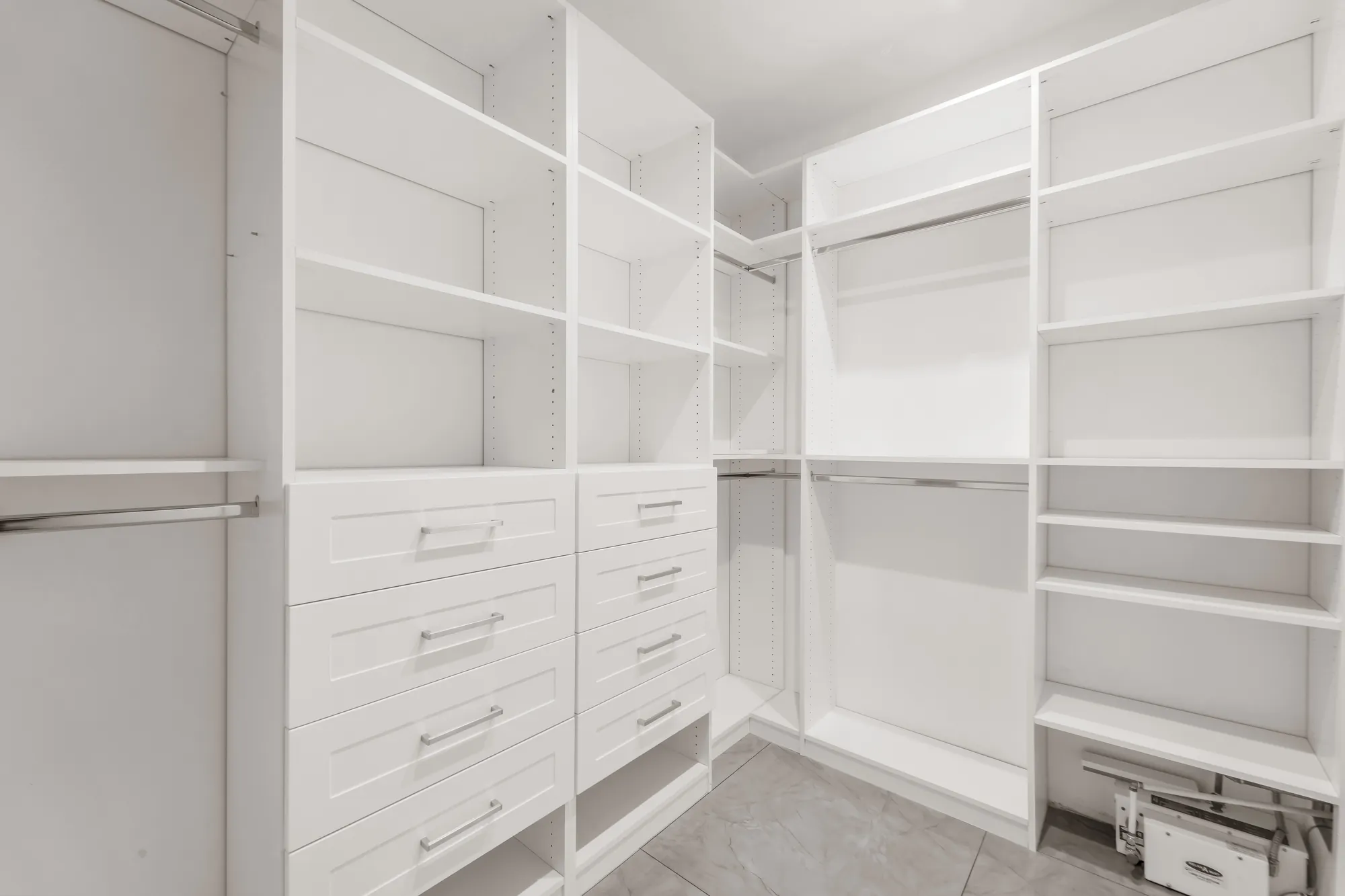 The walk-in closet: white built-in shelves, hanging rails and a bank of drawers