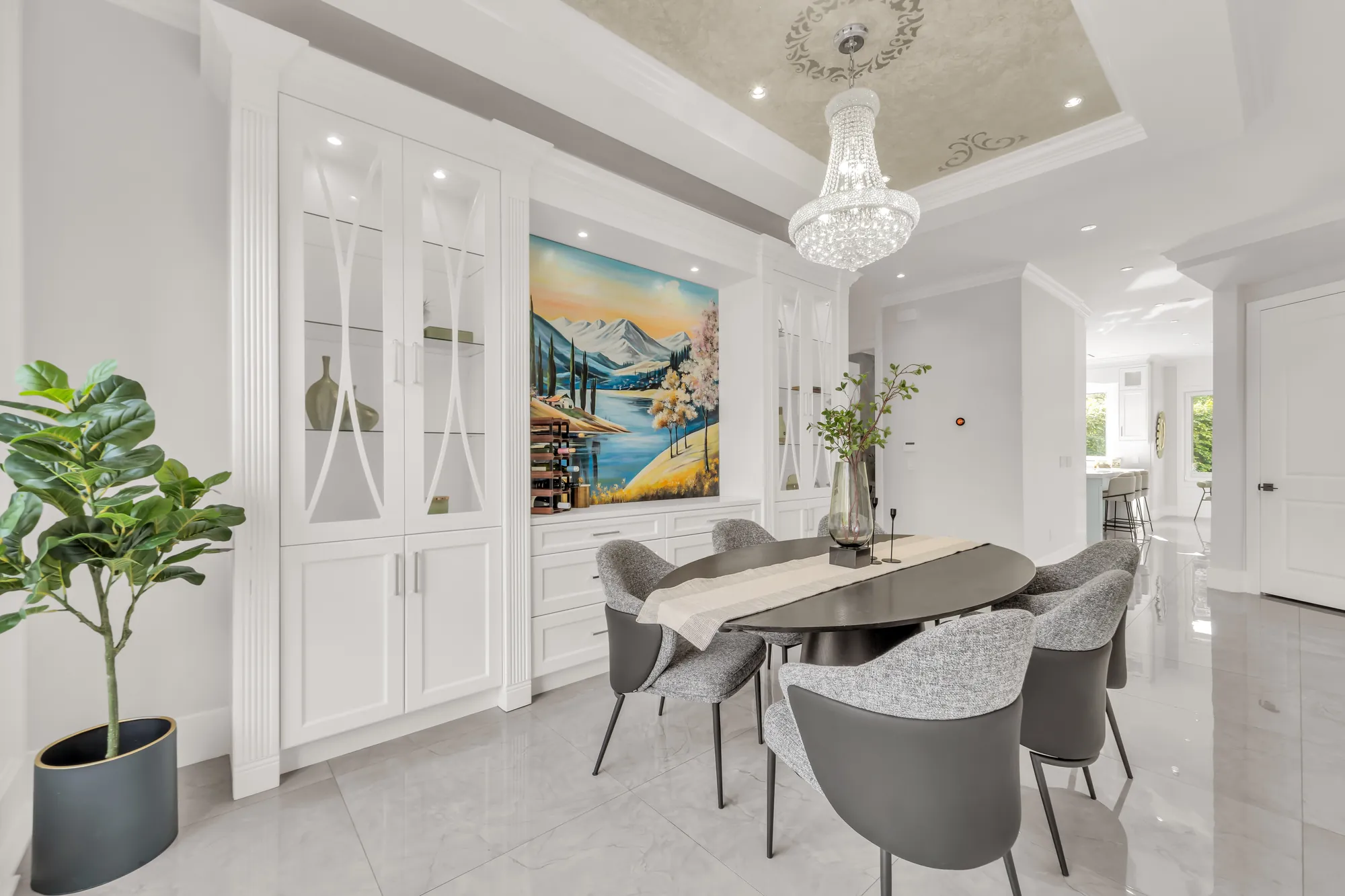 The dining room toward its built-in cabinets: glass-front upper doors, panelled lower doors, the landscape painting, a potted fig tree, the hall beyond