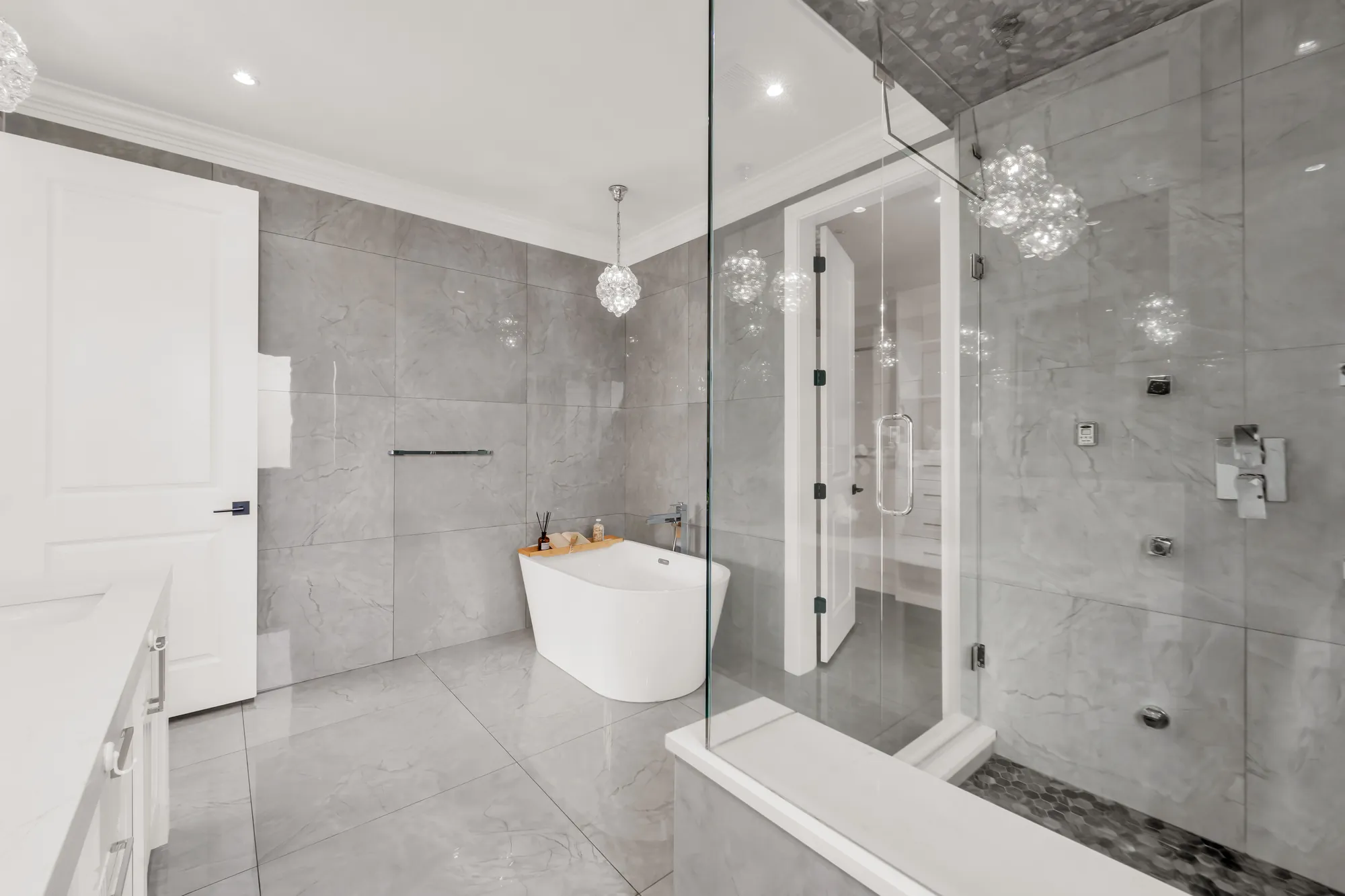 The primary bathroom toward the tub and the glass shower, a door at the left