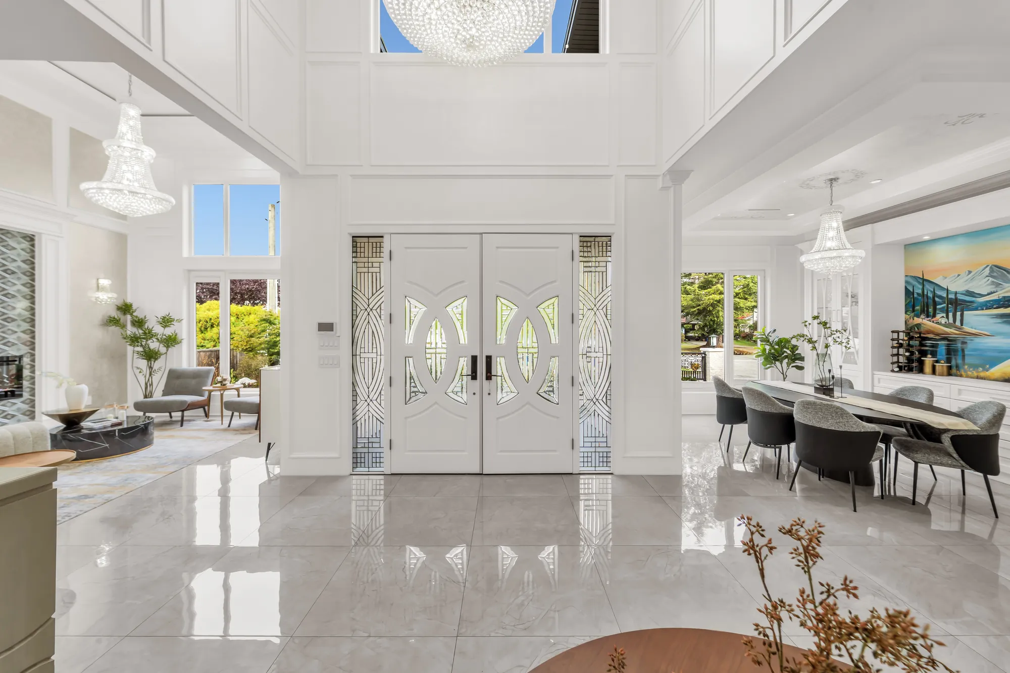 The front doors from inside: the double doors with leaded-glass panels and sidelights, two crystal chandeliers, the living room at the left and the dining room at the right