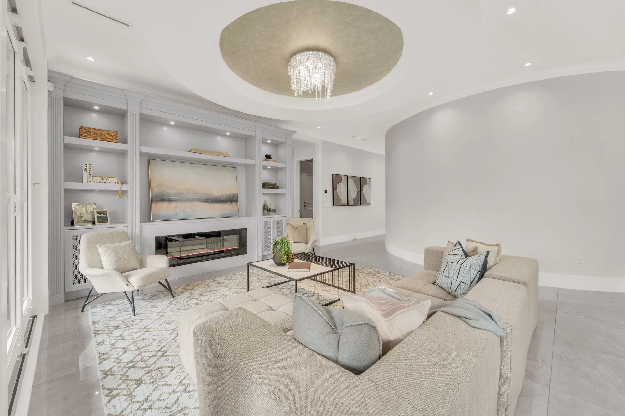 The family room toward the built-in wall and a curved wall at the right, the sectional and lounge chairs on a patterned rug