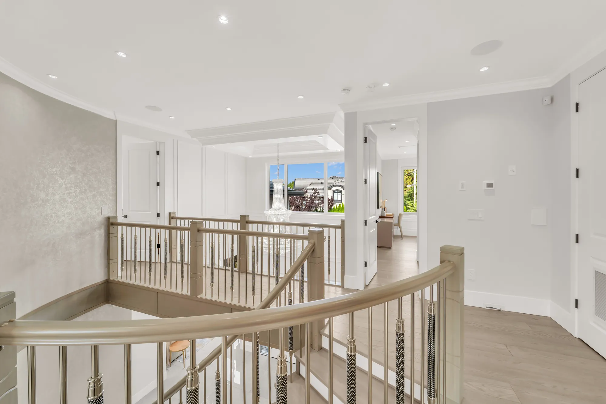 The upstairs hall: the curved stair railing in wood and metal around the stairwell, bedroom doors, a window at the far end