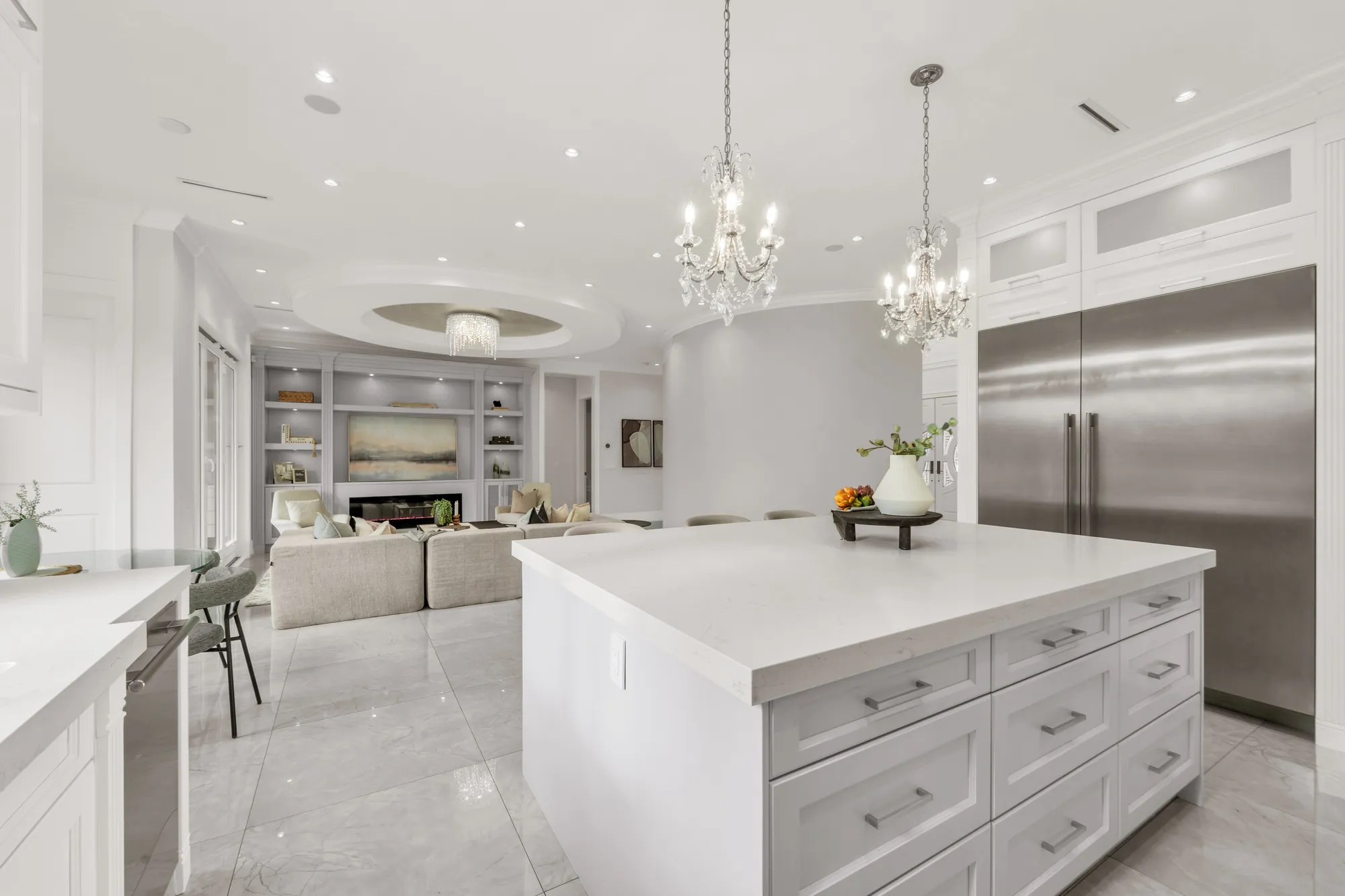 From the kitchen across the island to the family room and its built-in wall, the stainless refrigerator columns at the right