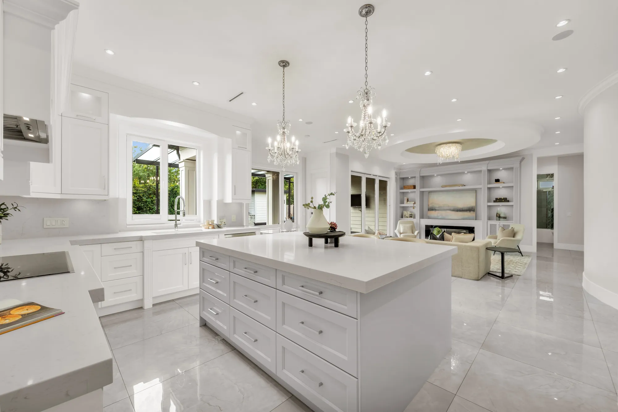 The kitchen toward the sink window and the family room beyond, the island with drawers in front, a curved wall at the right