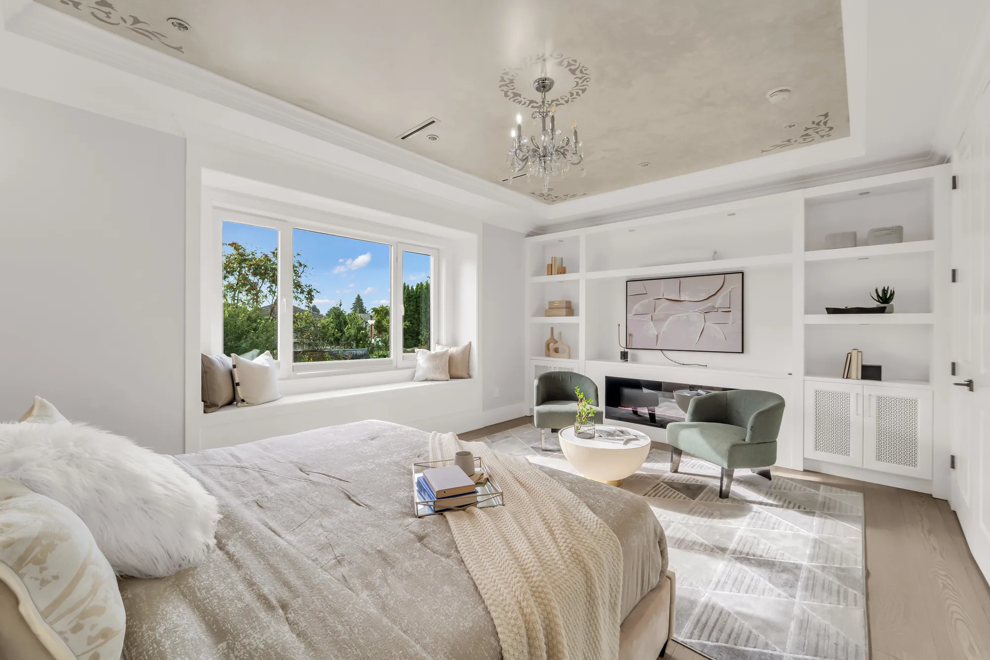 The primary bedroom toward its built-in wall of shelves and cabinets, the window seat at the left, the bed in the foreground